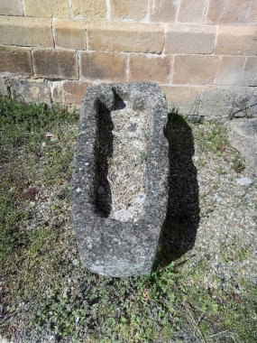 Kilisenin duvarının yanına desenli yüzeyi olan eski taş bir lahit.