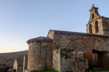 Günbatımında çan kulesi ve kemerli kapısı olan antik Romen taş kilisesi.