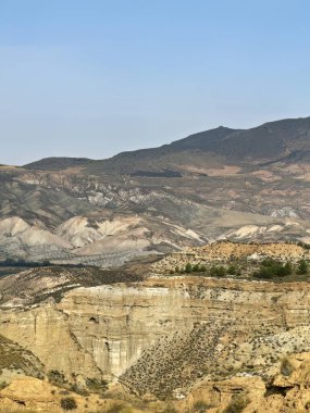 Kuru tepelerin geniş manzarası ve doğal bir geopark ortamındaki çok renkli kaya katmanları.