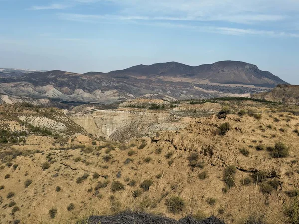 Kuru tepelerin geniş manzarası ve doğal bir geopark ortamındaki çok renkli kaya katmanları.