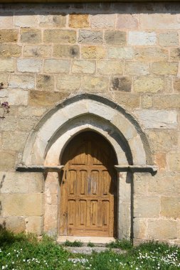 Palencia İspanya 'da taş kemerli ve koyu ahşap kapılı Roma kilisesi kapısı.