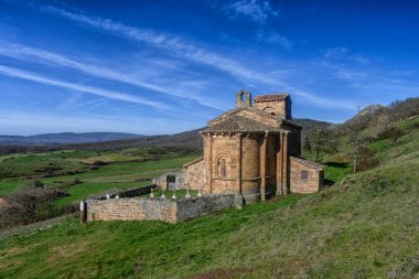 Taş duvarları, kırmızı fayanslı çatısı ve Palencia kırsalında kurulu çan kulesi olan tarihi Roma kilisesi..
