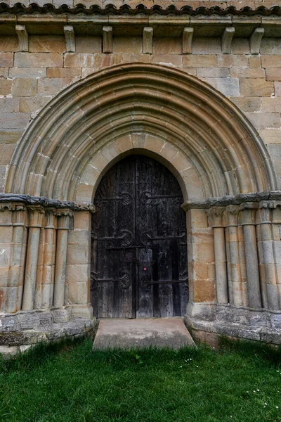 Palencia 'daki Santa Eulalia inzivasında yarı dairesel kemerli ve ahşap kapılı Romen taş portalı..