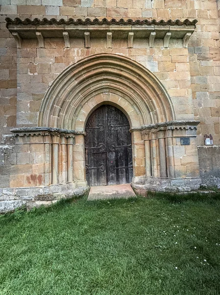 Palencia 'daki Santa Eulalia inzivasında yarı dairesel kemerli ve ahşap kapılı Romen taş portalı..