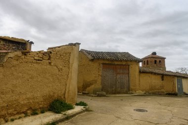 Sessiz kırsal bir köyde, çimen tarlalarıyla çevrili kiremitli çatıları olan eski kerpiç evleri.