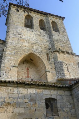 Palacios del Alcor, Palencia 'da yeşil bir yamaçta taş çan kulesi olan tarihi kırsal kilise.