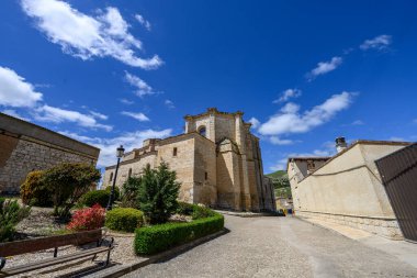 Palenzuela, Palencia 'daki San Juan Bautista Kilisesi' nin panoramik manzarası, Romanesk ve Gotik unsurların çatıların üzerinde yükseldiğini gösteriyor.