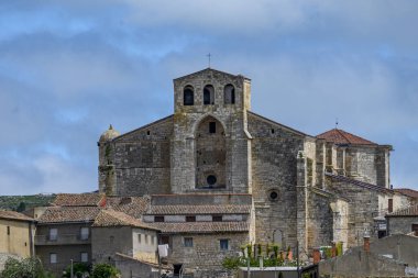 Palenzuela, Palencia 'daki San Juan Bautista Kilisesi' nin panoramik manzarası, Romanesk ve Gotik unsurların çatıların üzerinde yükseldiğini gösteriyor.