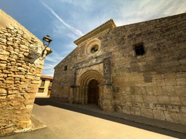 Sessiz bir İspanyol köyünde, kemer girişi ve taş duvarları olan antik Roma kilisesi cephesi.