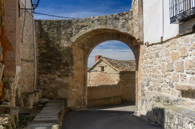 İspanya 'nın Castilla y Leon kentindeki Castrillo de Onielo eski kentsel duvarının bir parçası olan tarihi taş evlerle dolu dar bir cadde.