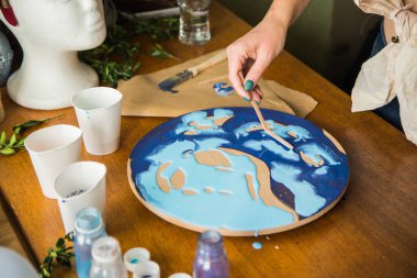 Kadın sanatçı, mermer efektli soyut akışkan sanat eserleri üzerinde çalışır, güzel genç kadın ressamın portresini yakından çekerek ahşap bir masa üzerinde yaratıcı çalışma alanında sanat eserleri yaratır.