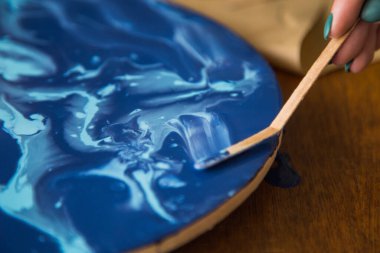 Kadın sanatçı, mermer efektli soyut akışkan sanat eserleri üzerinde çalışır, güzel genç kadın ressamın portresini yakından çekerek ahşap bir masa üzerinde yaratıcı çalışma alanında sanat eserleri yaratır.