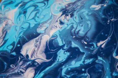 Kadın sanatçı, mermer efektli soyut akışkan sanat eserleri üzerinde çalışır, güzel genç kadın ressamın portresini yakından çekerek ahşap bir masa üzerinde yaratıcı çalışma alanında sanat eserleri yaratır.