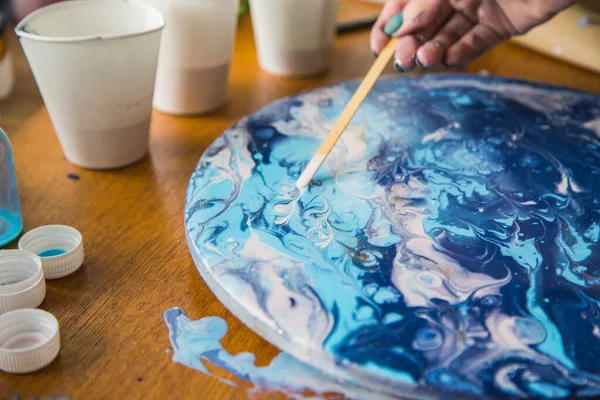 Kadın sanatçı, mermer efektli soyut akışkan sanat eserleri üzerinde çalışır, güzel genç kadın ressamın portresini yakından çekerek ahşap bir masa üzerinde yaratıcı çalışma alanında sanat eserleri yaratır.