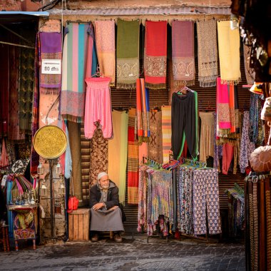  Onun kumaş dükkanında oturan bir adam