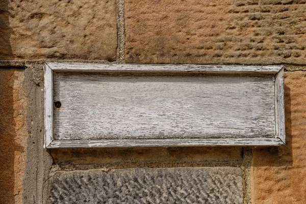 Taş Duvarda Yıpranmış Boş Bir Tahta Tabela — Stok fotoğraf