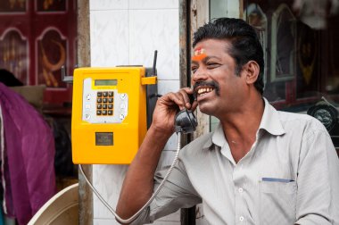 Indian man using a public telephone clipart