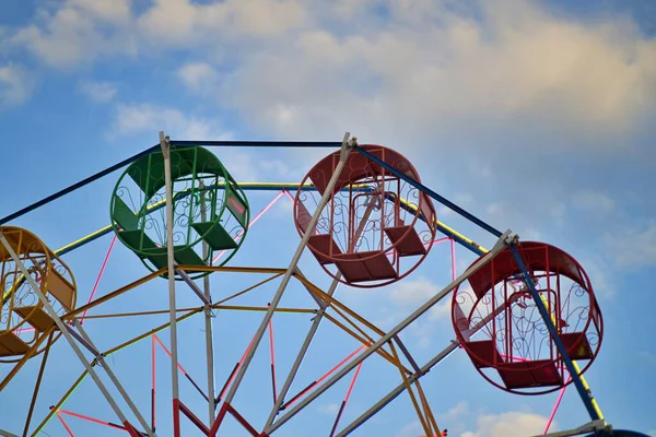 Yerel bir eğlence parkında küçük bir dönme dolap, mavi gökyüzü arka planına karşı..