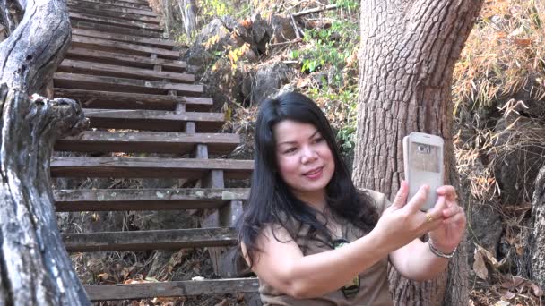 Bonita mujer asiática en el bosque con un teléfono inteligente . — Vídeo de stock
