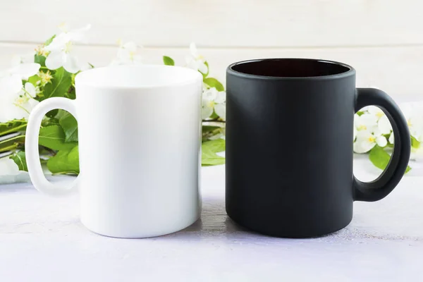 White and black mug mockup with spring apple blossom. Coffee cup mockup. Empty mug mockup for product presentation.