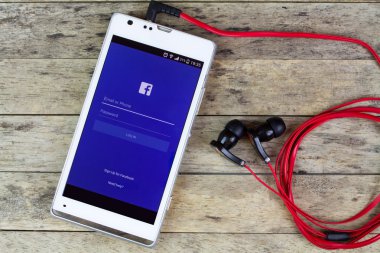 Tıkamak Kan, Tayland - 02 Eylül 2015: kulaklık, facebook müzik akışı ile akıllı telefon tarafından facebook kullanma