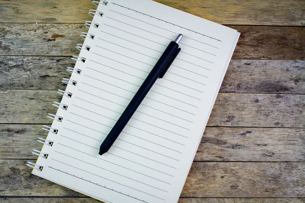 Caderno e caneta em uma mesa de madeira — Fotografia de Stock