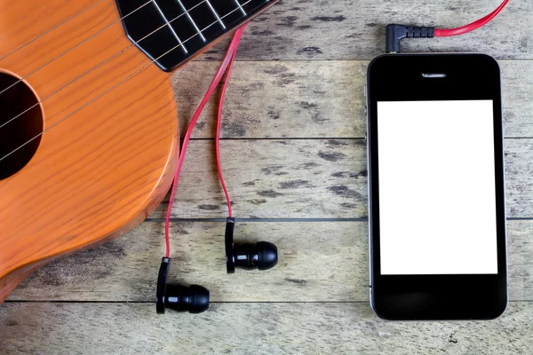 Guitar, earphones and smart phone on a wood table