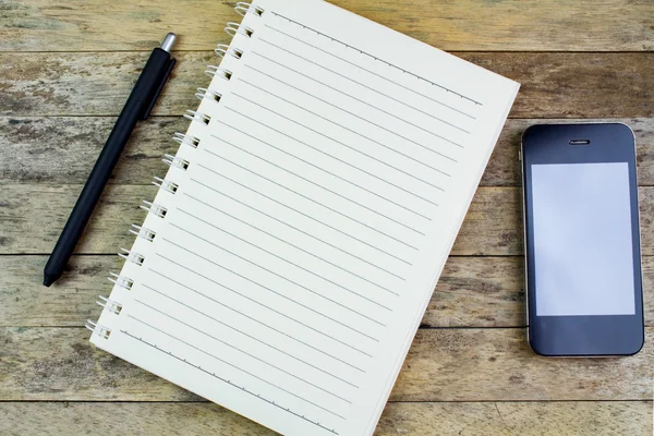 Notebook, caneta e smartphone em uma mesa de madeira — Fotografia de Stock