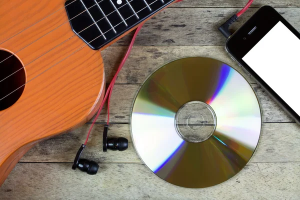 Chitarra, CD, smartphone e auricolari su un tavolo — Foto Stock