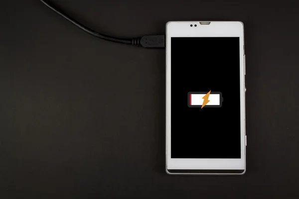 Smartphone di ricarica su sfondo, batteria scarica — Foto Stock