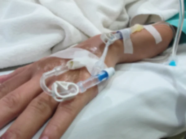 Main du patient avec perfusion intraveineuse saline (iv), Effet flou — Photo