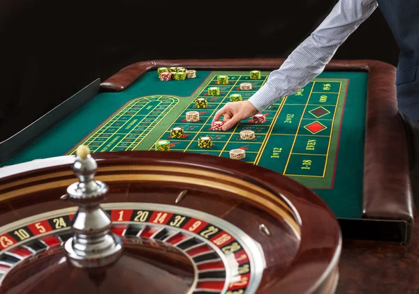 Roulette et piles de jetons de jeu sur une table verte . — Photo