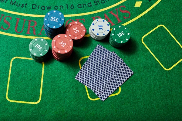 Casino chips and deck of cards lying on casino table — Stok fotoğraf