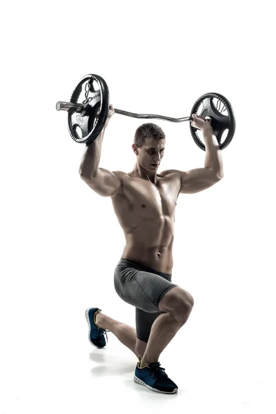 Muscular man standing on knee, holding barbell over his head — 스톡 사진