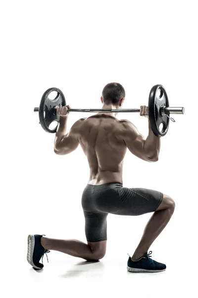 Fitness man standing on knee and holding barbell, rear view — ストック写真