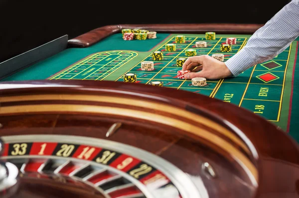 Roulette und stapelweise Spielchips auf einem grünen Tisch. — Stockfoto