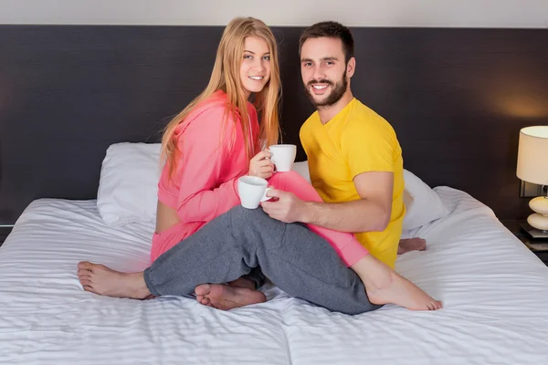 Feliz joven pareja desayunando en la cama en casa — Foto de Stock