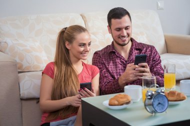 Cute young couple having breakfast, photographs at mobile phone