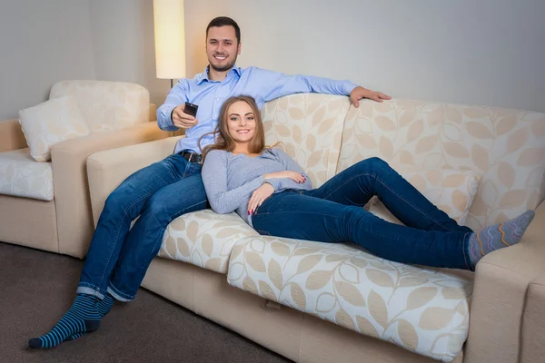 Happy couple sitting on sofa watching television together — Φωτογραφία Αρχείου