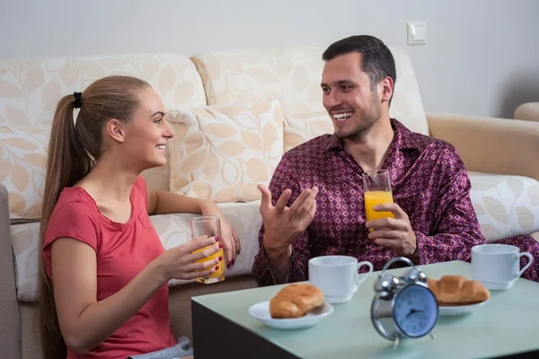Linda pareja joven desayunando, comiendo croissants, bebiendo jugo de naranja . — Foto de Stock