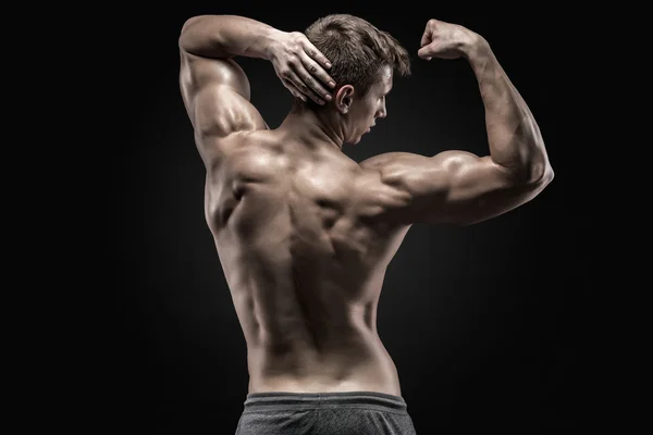 Joven musculoso sano mostrando músculos de la espalda y del bíceps — Foto de Stock