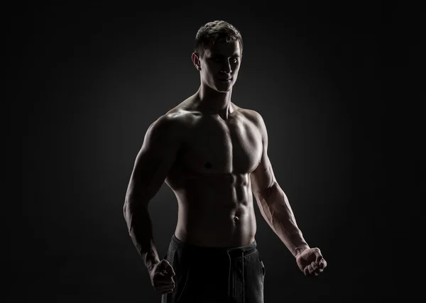 Sexy shirtless bodybuilder posing, looking at camera on black background. — Stock Photo, Image