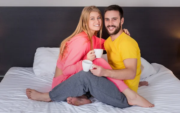 Feliz joven pareja desayunando en la cama en casa — Foto de Stock