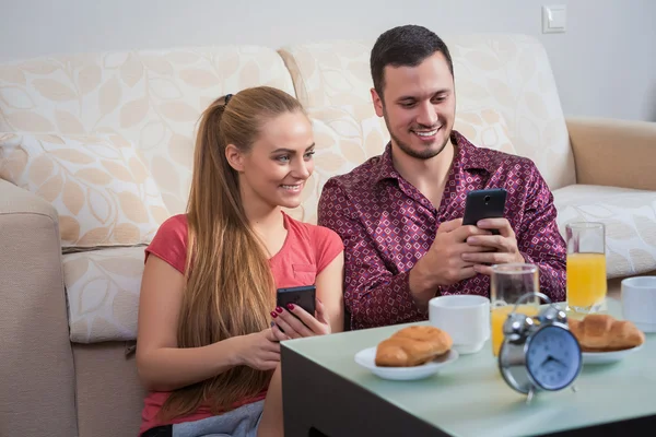 Linda pareja joven desayunando, fotografías en el teléfono móvil — Foto de Stock