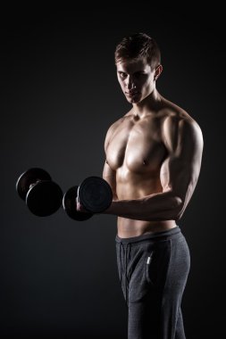 Yakışıklı adam dumbbells ile mükemmel vücut siyah arka plan üzerinde gösterilen.