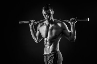 Güçlü adam onun omuzlarında halter tutan kameraya bakan