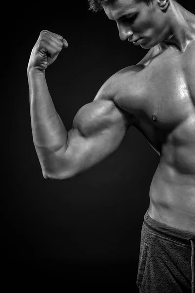 Homem de fitness mostrando seu tríceps, músculos do bíceps no backgro preto — Fotografia de Stock