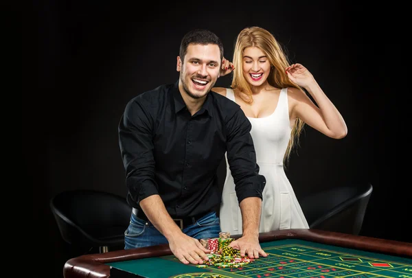 Young couple celebrating win at roulette table in casino.