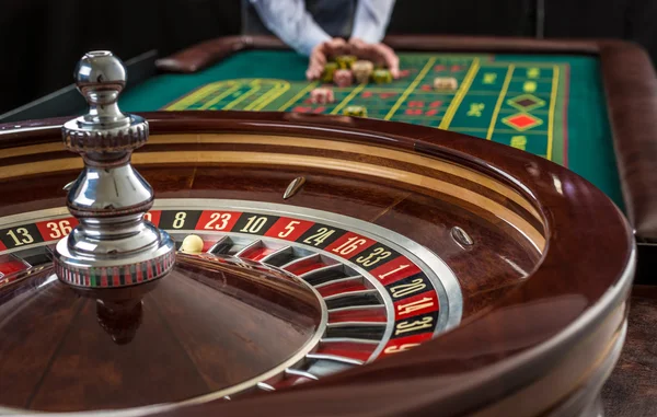 Roulette et piles de jetons de jeu sur une table verte . — Photo