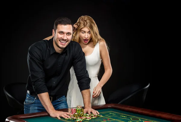 Pareja joven celebrando victoria en la mesa de ruleta en el casino . — Foto de Stock